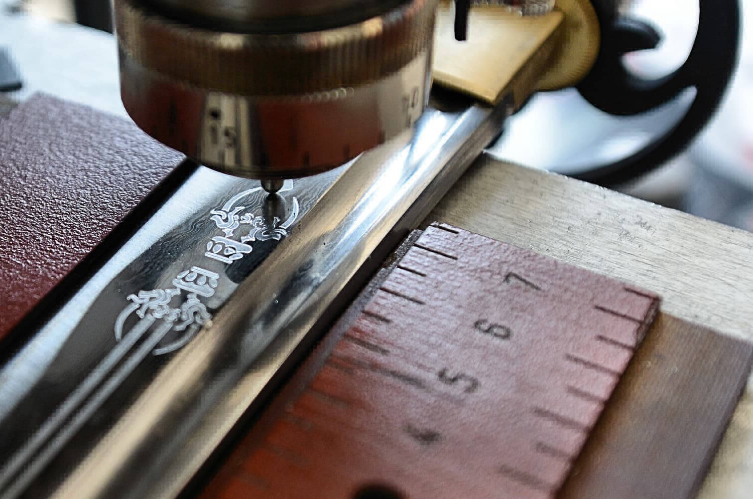 Gravure mécanique (pointe diamant) sur une lame de katana (sabre japonais) réalisée par notre partenaire Atelier Signature (photographie Philippe Contal)